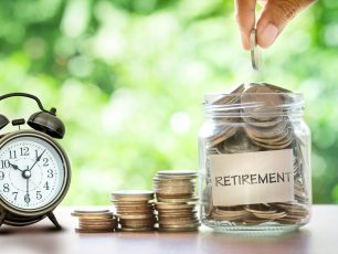 a person putting money in a jar next to an alarm clock.